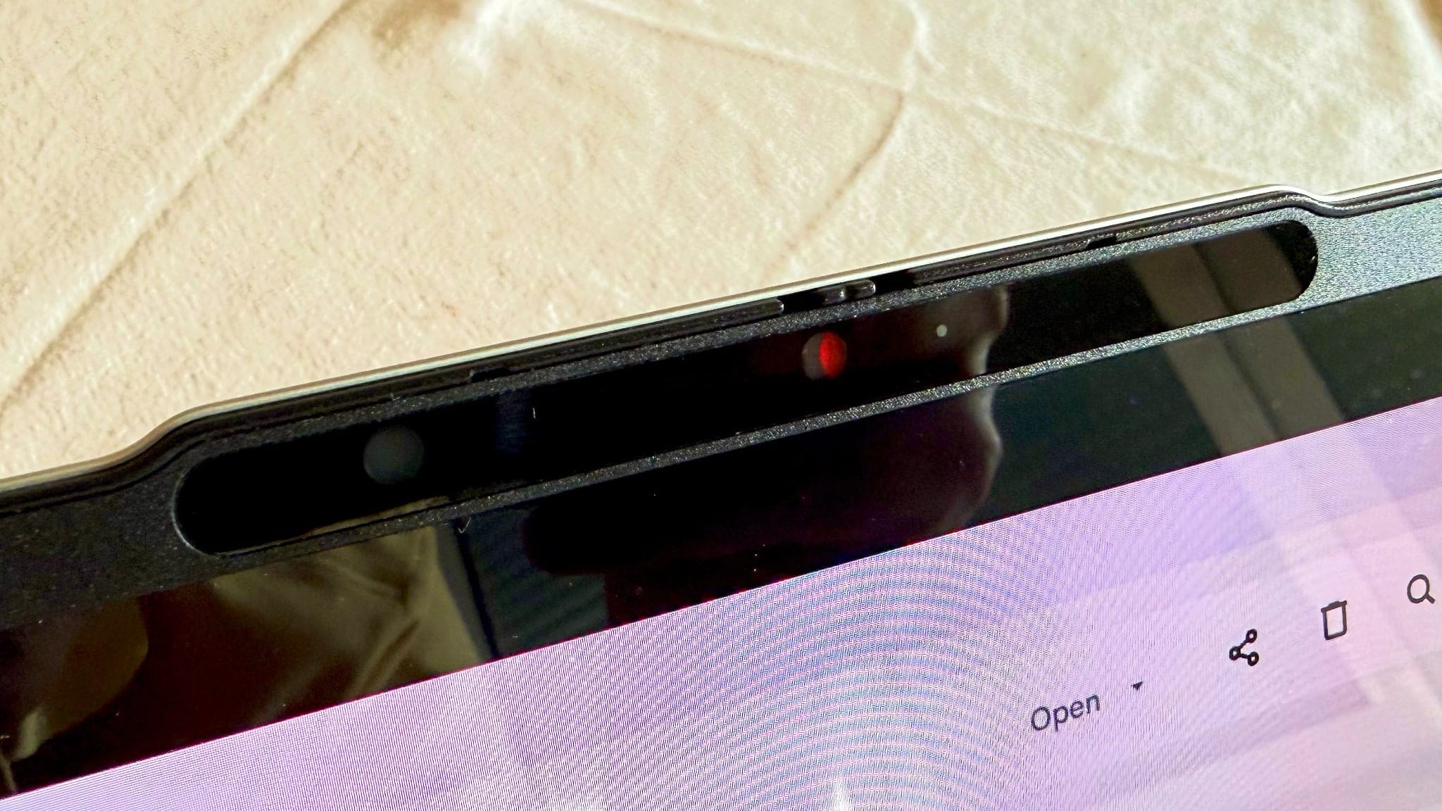 Webcam with its red privacy shutter closed in the raised lip above the display